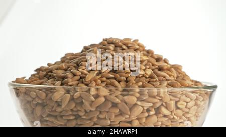 Nuts sunflower rotate are on a table in a plate. Snack in transparent dish on an isolated white background are spinning moving. Delicious and healthy Stock Photo