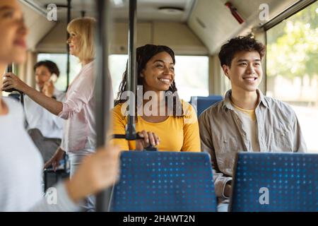 Young asian guy and black lady taking bus together Stock Photo