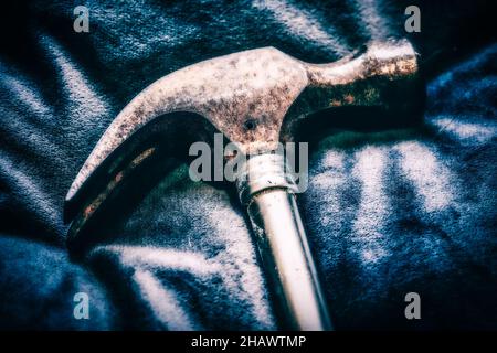 Macro photography, side view of a shiny steel claw hammer, hand tool on a mottled blue background, in a dark and moody style with deep dark shadows Stock Photo