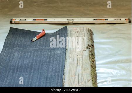 The master prepares bitumen tape for installation, protection of a floor from moisture, measurement and cutting. Stock Photo