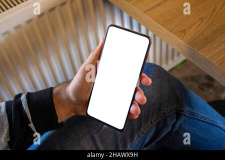 Man using smartphone, mockup image of a man hand holding black mobile phone with blank white screen while sitting in a cafe. Stock Photo