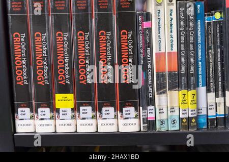 Six books of  The Oxford handbook of Criminology on book shelf next to other books in a public library England UK Stock Photo