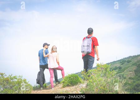 Three friends stands in nature and looks in different diections with green  nature and empty sky in the background. bank space image of lifestyle and Stock Photo