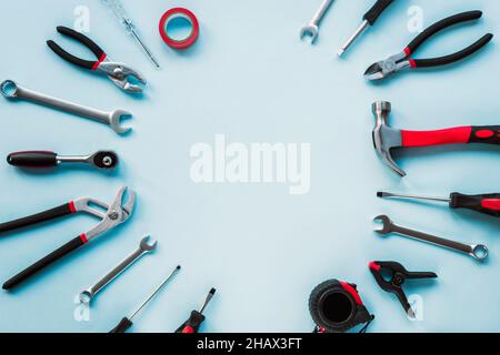 Working tools hammer, screwdriver, pliers, spanner and meter on light blue background. Top view, flat lay, copy space Stock Photo