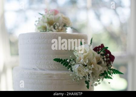 Beaautiful white three tier wedding cake with Pink flowers cake topper and flowers decoration Stock Photo