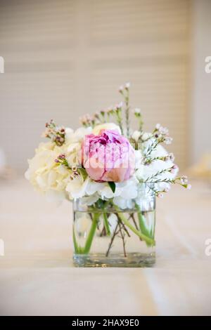 White carnations and pink peony floral centerpiece in small glass jar Stock Photo