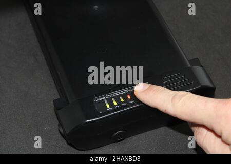 Finger Pressing an Electric Bike Lithium Battery Button to Check Power Levels Indicated by Green and Red Lights Stock Photo