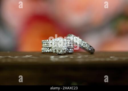 Bride and Groom white gold wedding rings on wood jewelry box with flowers in the background Stock Photo