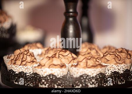 Black ast iron ornate cupcake tower with chocolate cupcakes that have chocolate fuge drizzle Stock Photo