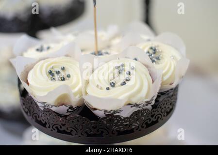 Black ast iron ornate cupcake towers with vanilla cupcakes that have blue and silner sprinkles Stock Photo