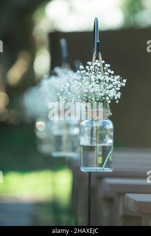 Babies breath flowers in mason jars hanging from sheapards hook in wedding ceremony isle Stock Photo