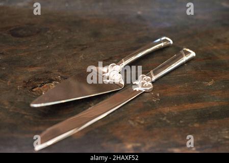 Silver cake serving utensils with heart designs on wood table Stock Photo