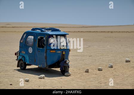 Blue tuk tuk three wheel taxi short distance transportation sits at peru natural reserve beach parking lot waiting for tourist to pay for use. Stock Photo