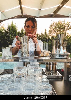 MILANP, ITALY - Nov 04, 2021: A vertical shot of a young Caucasian young female bartender making cocktails in the outside. Stock Photo