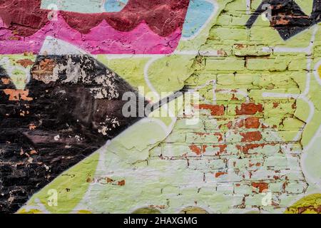Colorful close up of graffiti on a brick and concrete wall including colors mainly of black pink and green. Stock Photo