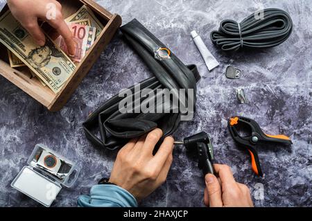 Payment for bicycle services. Money in hand. Bicycle workshop cash desk. Inflating the tube for the bicycle wheel. Stock Photo