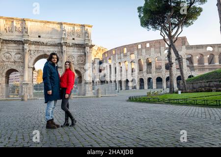 Young couple traveling to Rome. The young couple poses in front of the Arch of Titus. The blonde woman in her red jacket puts her hand on her boyfrien Stock Photo