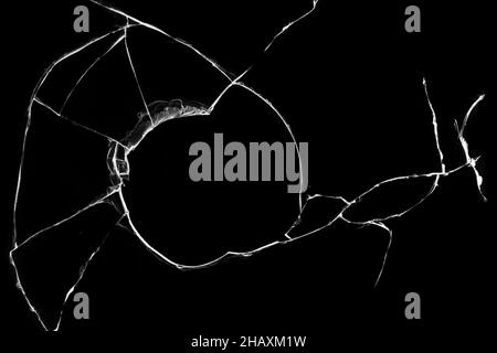 Cracked broken glass, hole in a broken window texture on a black background. Stock Photo