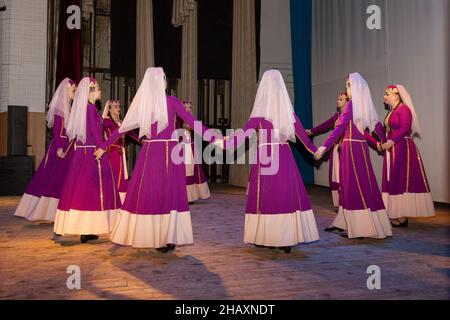 Omsk, Russia. 05 December, 2021. Ten girls in ethnic Armenian costumes dance the national Blooming cherry ritual dance in form the roundelay. Performa Stock Photo