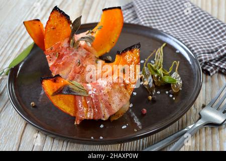 Hokkaido pumpkin gaps wrapped in bacon with sage leaves and thyme, baked in olive oil Stock Photo