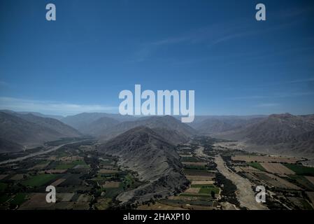 View of andean farmland with mountains and blue sky behind from small passenger plane taking tourists on trip to see nasca lines ancient geoglyphs. Stock Photo