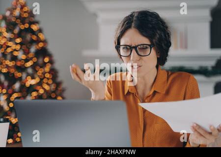 Stressed Italian businesswoman feels angry with error or mistake while remotely working on Christmas Stock Photo