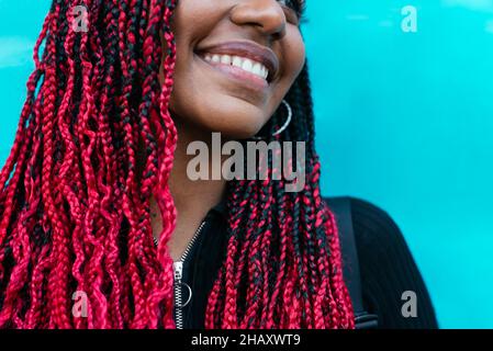 Cropped unrecognizable content black Woman with Afro braids standing on blue background Stock Photo