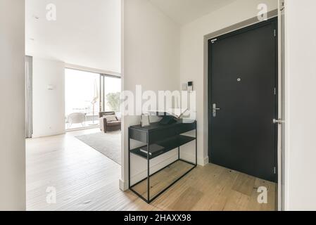 Black door in spacious light corridor in apartment with minimalistic design in daytime Stock Photo