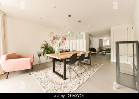 Interior of contemporary spacious apartment with dining zone furnished with table and chairs placed on carpet in daylight Stock Photo