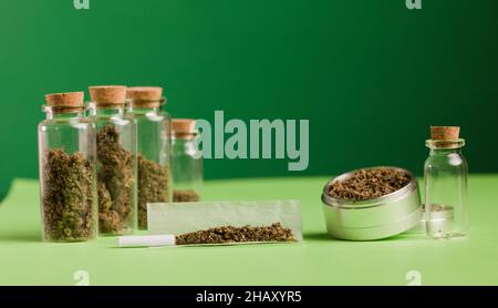 Chopped marijuana on grinder, on cigarette paper with filter and airtight  glass bottle, process for the production of marijuana cigarro Stock Photo -  Alamy
