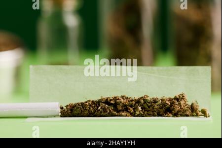 Chopped marijuana on grinder, on cigarette paper with filter and airtight  glass bottle, process for the production of marijuana cigarro Stock Photo -  Alamy