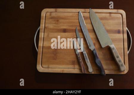 Different sized knives arranged in a row on a cutting board ordered from smallest to largest Stock Photo