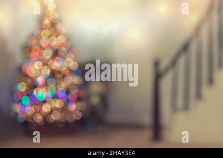 Blur Christmastime Background. Cozy Xmas Decorated Home. Bokeh Glowing Garland on Christmas Tree. Merry Christmas and Happy New Year. Stock Photo
