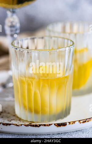 Two glasses of vodka cocktails with lemon and ice cubes on a table Stock Photo
