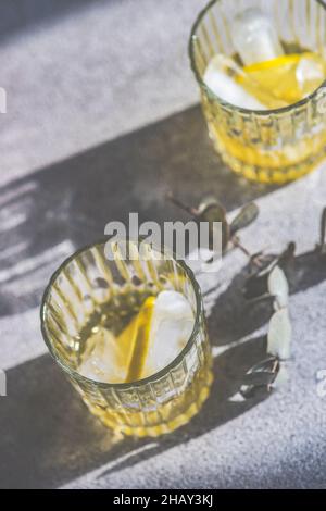 Two tall cocktail glasses with pink gin and tonic garnished with large  crystals of salt on an edge of a glass, large piece of ice, peppermint  Stock Photo - Alamy