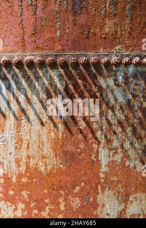 Shadows cast by a line on nuts over a rusty tank.CuÃ±apirÃº dam, Rivera, Uruguay. Stock Photo