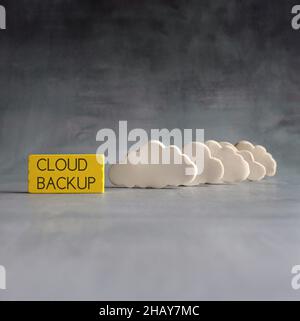 Cloud computing concept. White clouds and wooden cubes with text CLOUD BACKUP Stock Photo