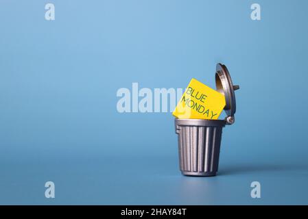 Blue Monday or Monday Blues concept. Wooden cube with text BLUE MONDAY inside dustbin, trash can. Copy space for text Stock Photo