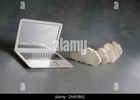 Cloud computing concept. Laptop and white clouds. Stock Photo