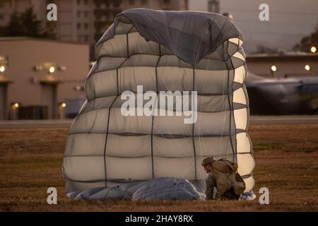 A Marine assigned to the 3rd Reconnaissance Battalion, 3rd Marine Division, recovers his parachute after conducting a high altitude, low opening (HALO) jump over Yokota Air Base, Japan, Dec. 13, 2021. U.S. Marines and an Air Force Survival, Evasion, Resistance and Escape (SERE) specialist conducted week-long jump training using Air Force and Navy aircraft. The training supports the U.S. Indo-Pacific Command’s dynamic force employment (DFE) concept through agile combat employment (ACE), which supports the National Defense Strategy effort to conduct training with joint partners while maintaining Stock Photo