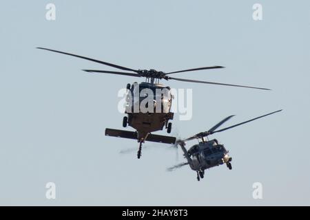 Two MH-60S Sea Hawks, assigned to Helicopter Sea Combat Squadron (HSC) 12, prepare to land after conducting a high altitude, low opening (HALO) parachute jump training, Yokota Air Base, Japan, Dec. 13, 2021. Marines assigned to the 3rd Reconnaissance Battalion, 3rd Marine Division and an Air Force Survival, Evasion, Resistance and Escape (SERE) specialist conducted week-long jump training using Air Force and Navy aircraft. The training supports the U.S. Indo-Pacific Command’s dynamic force employment (DFE) concept through agile combat employment (ACE), which supports the National Defense Strat Stock Photo