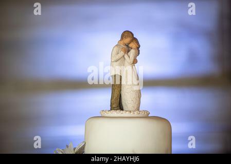 Earthy three tier wedding cake with canvass lace and bows and sunflowers on wood bark stand and wood door background Stock Photo