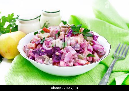 Finnish Rosoli salad with herring, beets, potatoes, pickled or pickled cucumbers, carrots, onions and eggs, dressed with mayonnaise in bowl on wooden Stock Photo