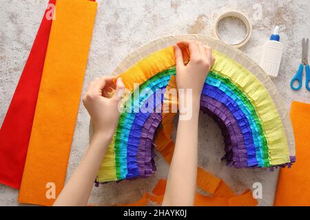 Woman making Mexican pinata in shape of rainbow on grunge background Stock Photo