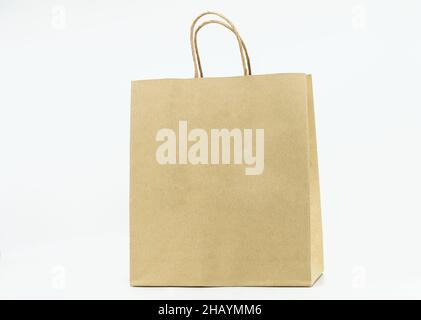Isolated brown paper bag on white background, brown paper bag with paper handle, blank space on the front for design elements. Stock Photo