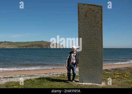 Man leaning against Emigration Stone, Cromarty, Highlands, Scotland, UK Stock Photo