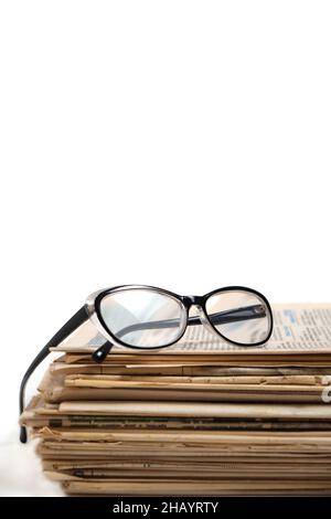 Stack of old newspapers and reading glasses on a white background Stock Photo
