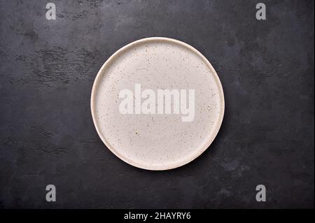 Top view empty white rustic ceramic plate with on black graphite background, copy space Stock Photo