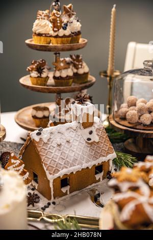 Traditional Christmas gingerbread house and cupcakes on the festive mood table Stock Photo