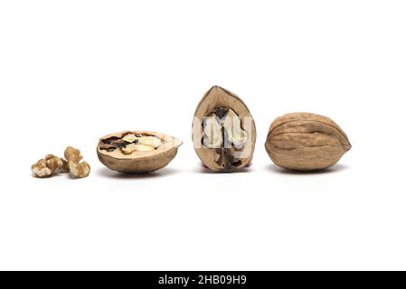 three walnuts one closed two halves side by side seen outside and inside with shadow isolated on white background Stock Photo